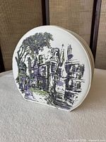 Front of round white vinyl carrying case with printed street scene