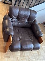 Front top view of brown leather armchair showing tufted cushions and wood frame
