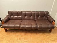 Front view showing four tufted leather cushions and wooden legs