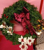 Full view of wreath showing velvet bow, poinsettias, pine cones, berries and gold ornaments