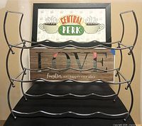 Front view of chrome wine rack with Central Perk print behind