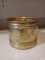 Front view of brass planter showing patina and banding