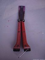 Saw in folded position showing wooden handles, hinge bolts, partial blade with teeth