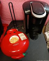 Overall view of all three items: Keurig brewer, quesadilla maker closed, wire holder