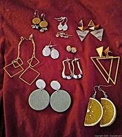 Full group view of all 11 earring pairs laid out on red fabric