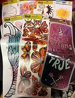 Group of eight packaged vinyl wall decal sheets showing butterfly, feather, mermaid, sun and text designs