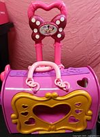 Front view of pink and purple Minnie Mouse rolling carrier with gold removable panel attached, telescoping handle extended