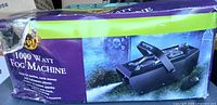 Front of boxed Spirit Halloween 1000W Fog Machine showing product image and damaged packaging