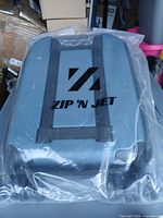 Front of suitcase in original plastic showing Zip 'N Jet logo