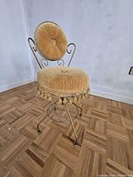 Full view of vanity chair showing frame, upholstery and tassel fringe