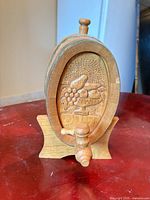 Front view showing carved motif, spigot, stand