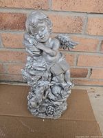 Front view of resin cherub statue with animals and flowers