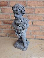 Front view of grey resin cherub statue holding fruit bowl