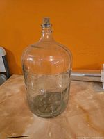 Full view of clear glass carboy with cork