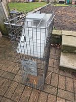 Full view of galvanized steel live animal trap standing upright on patio