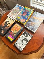 Top-down view of six VHS tapes on round wooden table