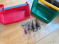 Overview of lot showing two toolboxes, three dinosaur figures, shark and screwdriver on wood floor