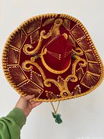 Full view of red velvet sombrero showing gold embroidery and sequins