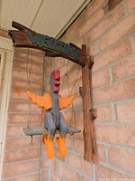 Front view of wooden rooster on swing sign mounted to brick wall