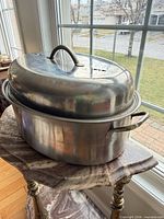 Oval aluminum roaster with lid stacked on pot