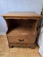 Front view of wooden side table with open shelf and drawer