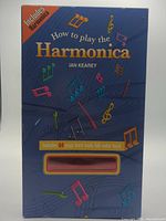 Front of boxed set showing title, author, note graphics, and window revealing harmonica