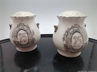 Front view of both ceramic shakers showing 25 wreath design