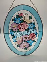 Full view of oval stained glass suncatcher showing floral design and text