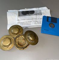 four brass buggy hubcaps with floppy disk and paper