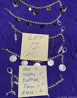 Four assembled silver-tone charm bracelets laid out – bell, glass bead, feather, coin charms visible