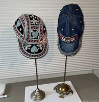 Two decorated baseball caps on their respective metal stands