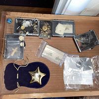 Drawer view showing star paperweight, pouch, five plastic cases of buttons and jewelry pieces, two zip bags