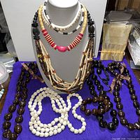 Full lot showing bust with multistrand and disc necklaces plus kukui nut and white bead strands on table