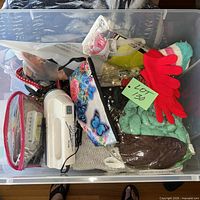 Overall view of clear bin showing gloves, knit blanket, clothes shaver, pouches