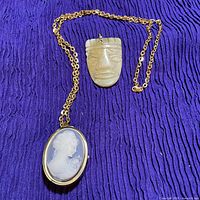 Cameo locket on chain and carved stone pendant overview