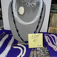 Group on bust: gray cabochon bib, white pendant, black/blue bead, seed bead strands