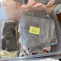 Clear tote holding folded grey jeans on top, note reading Lot 206 visible