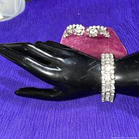Bracelet displayed on black hand form with earrings in background