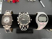 Three women's watches lined up on display stand