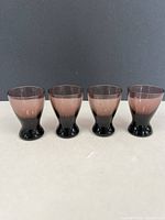 Front view of four amethyst shot glasses aligned side by side