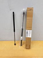 Two gas struts, one in plastic, with cardboard sleeve