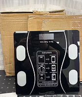 Front view of one scale showing display, sensor pads and boxed second unit behind