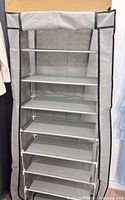 Assembled grey fabric shoe rack showing seven shelves and zippered cover