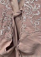 Close-up of silver floral embroidery on dusty rose fabric