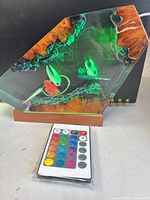 Full view of resin lamp showing characters illuminated green with remote in foreground