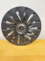 Front view of one matte black turbine-style hubcap