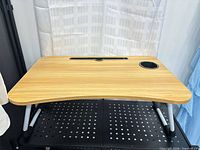Full view of lap desk on stand showing surface, slot, cup holder and folding legs