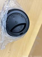 Close-up of single black 90 mm PP lid displaying sipping spout and molded caution text