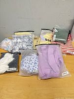 Overview of nine sealed Shein garment bags on tabletop