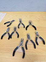 Eight individually wrapped precision pliers and cutters on tabletop